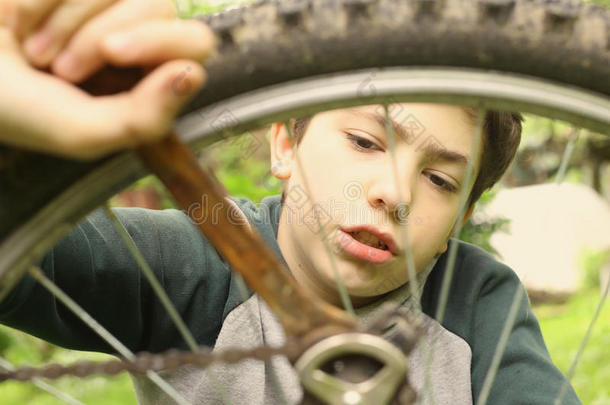 十几岁的青少年男孩修理自行车使疲惫关在上面夏照片