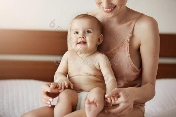 年幼的美丽的幸福的妈妈采用睡衣裤和她新生的婴儿sitting-room起居室