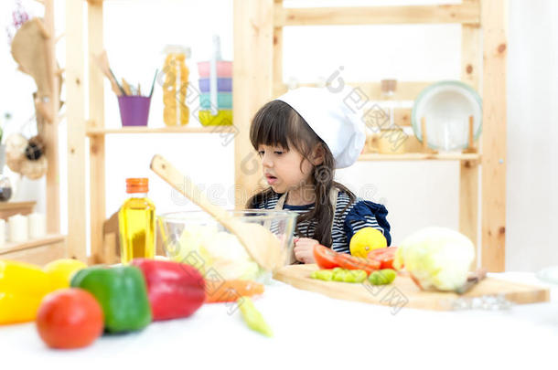 美丽的小孩女孩烹饪术和锋利的蔬菜