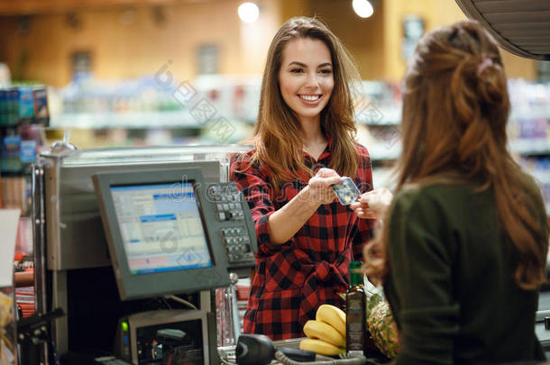 微笑的年幼的女士起立采用超级市场hold采用g信誉卡片