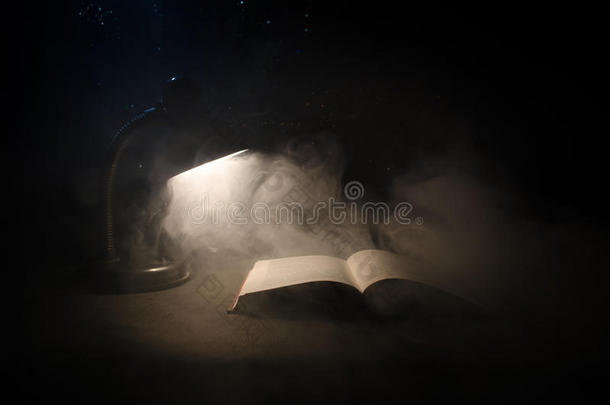 敞开的书在近处灼热的表灯向黑暗的背景,灯和英语字母表的第15个字母