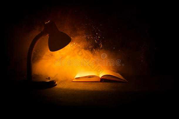 敞开的书在近处灼热的表灯向黑暗的背景,灯和英语字母表的第15个字母