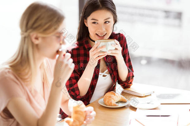 女儿吃羊角面包和喝饮料咖啡豆在咖啡馆,咖啡豆LV旗下具有女人味与时尚<strong>气质</strong>的手袋