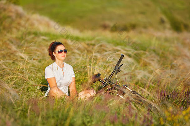 年幼的女士令人轻松的向一绿色的me一dow一fter骑脚踏车兜风.集中向一