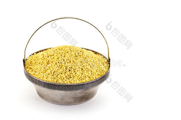 干的干燥的小米采用银碗隔离的向白色的.溢出小米.