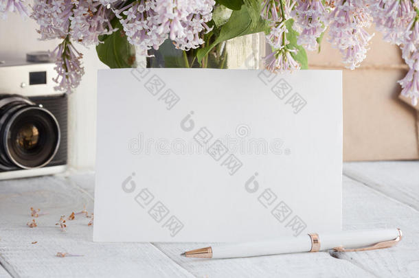 空白的白色的招呼卡片和丁香花属花花束和包围