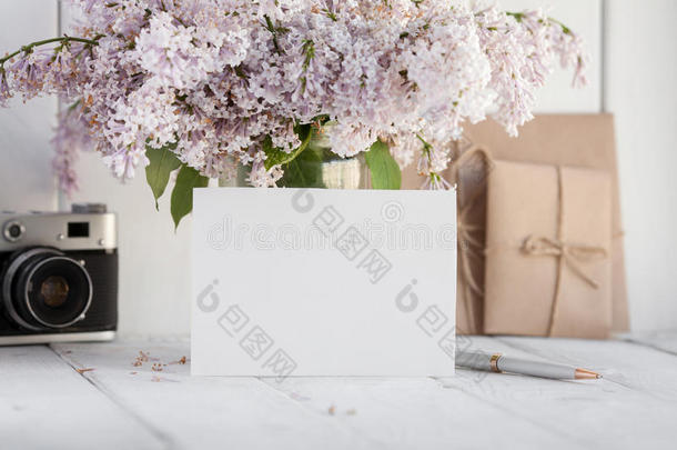 空白的白色的招呼卡片和丁香花属花花束和包围