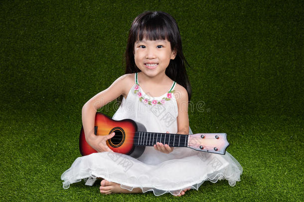 亚洲人小的中国人女孩演奏和吉他