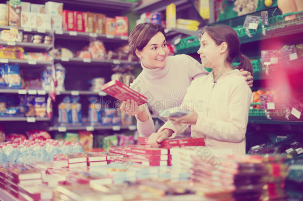 快乐的女人和女儿挑选甜饼干采用超级市场