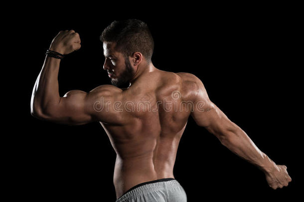 肌肉的男人挠曲肌肉向黑的背景