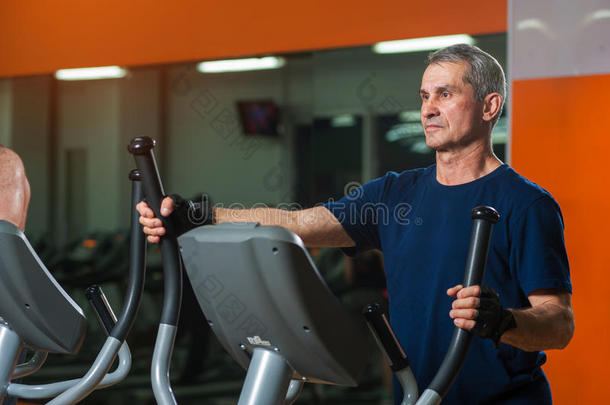 较高<strong>的</strong>男人锻炼向椭<strong>圆的</strong>机器采用健身房