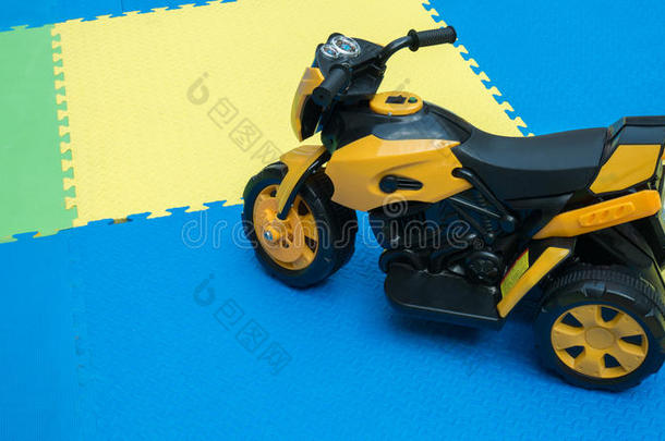 关在上面关于黄色的摩托车玩具向橡胶地面和复制品土壤-植物-大气连续体