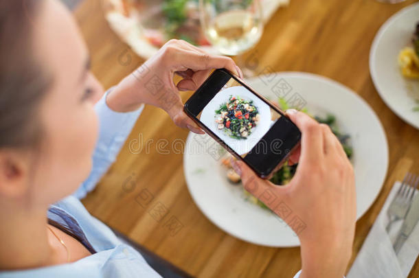 女人和智能手机摄影食物在咖啡馆