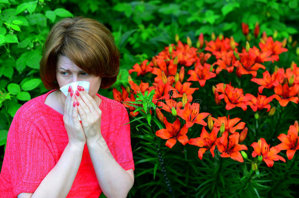女人和一过敏的鼻炎在近处百合花采用自然