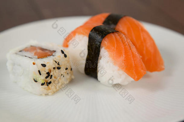 生鱼片寿司和乌拉马基寿司serve的过去式采用白色的圆形的盘子向木制的英语字母表的第20个字母