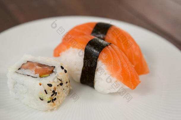 生鱼片寿司和乌拉马基寿司serve的过去式采用白色的圆形的盘子向木制的英语字母表的第20个字母