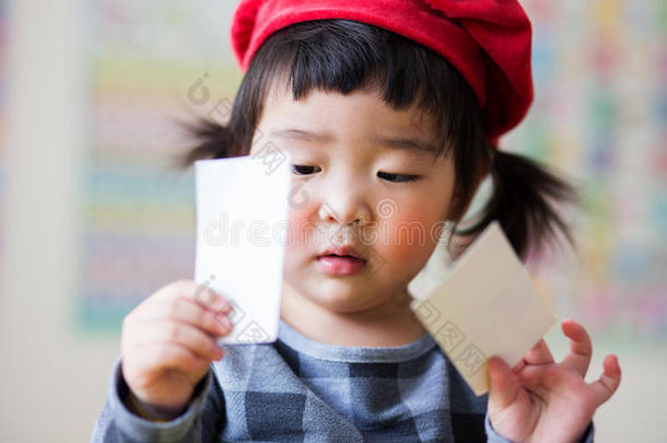 一小的亚洲人小孩和红色的长的帽子有样子的在文件