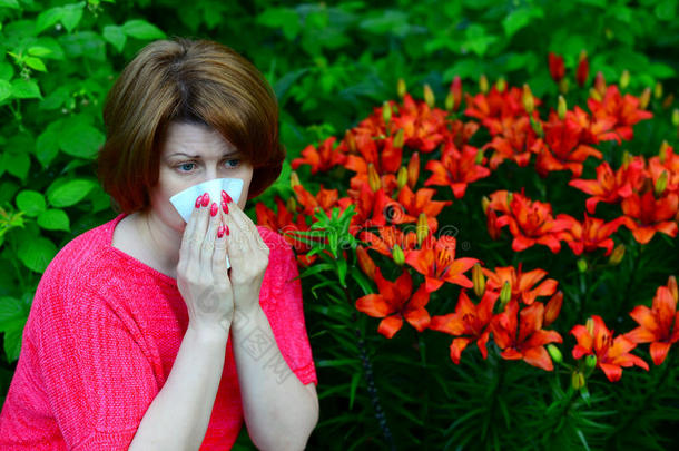 女人和一过敏的鼻炎在近处百合花采用自然