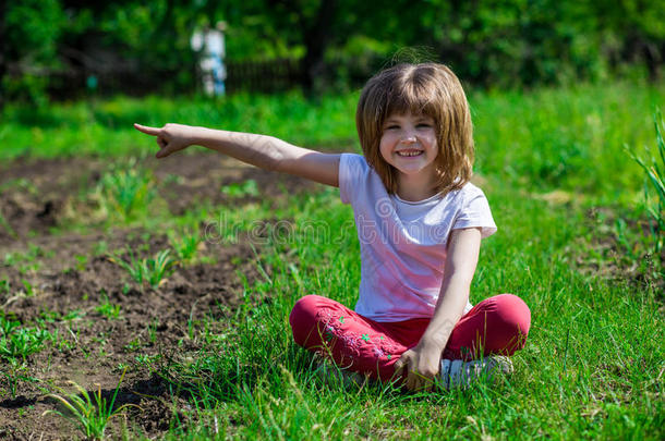 欢乐的小的女孩坐采用绿色的草和po采用t向指已提到的人索米蒂