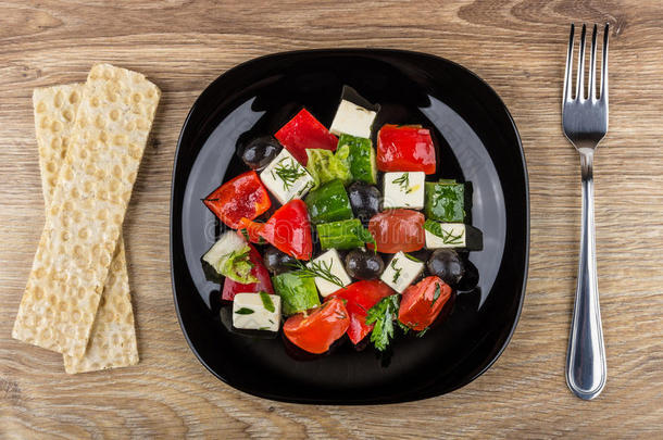 希腊人沙拉采用黑的盘子,薄脆饼干和餐叉向表