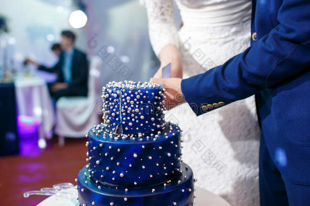 新娘和使整洁将切开蓝色婚礼蛋糕.