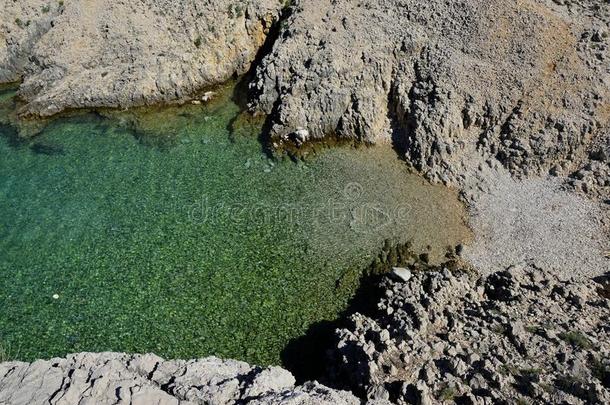 小的小海湾被环绕着的在旁边岩石,结晶清楚的水和心妈