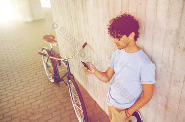男人和智能手机和固定的齿轮自行车向大街