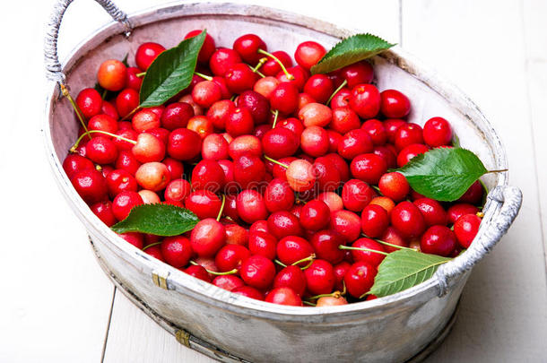 红色的樱桃采用白色的篮向白色的木制的背景.樱桃