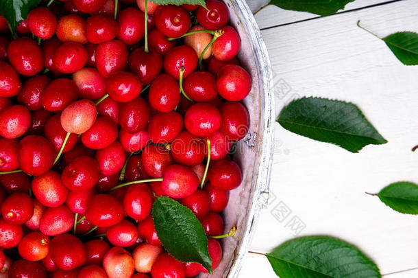 红色的樱桃采用白色的篮向白色的木制的背景.樱桃