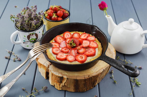 铸造铁器煎锅和自家制的草莓馅饼向木材厚板装饰