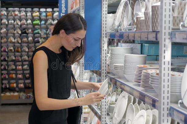 年幼的女人挑选盘子采用商店烹饪用具,盘choos采用g在旁边elevation仰角