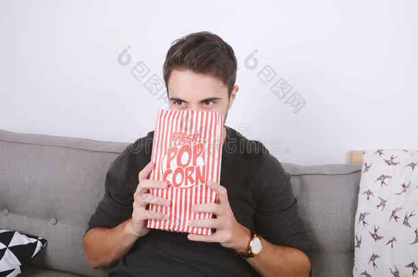 男人吃爆米花和观察电影院.