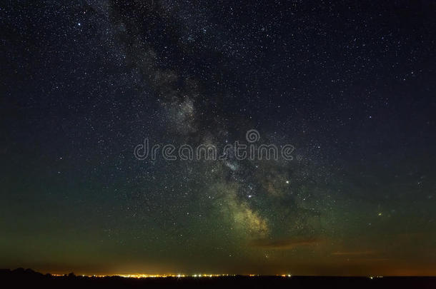 布满星星的夜天和指已提到的人像牛奶的道路越过城市和照明.