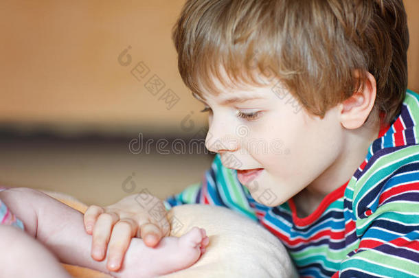 小的小孩男孩接吻的和演奏和脚关于新生的婴儿.