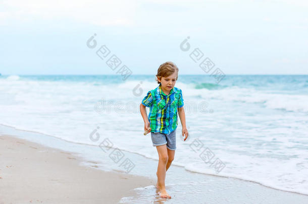 小的小孩男孩跑步向指已提到的人海滩关于洋