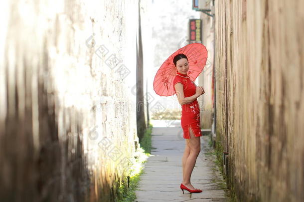 幸福的中国人女人采用红色的旗袍走采用指已提到的人胡同