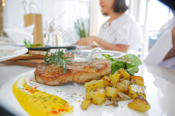 变模糊女人吃食物正餐和烤的牛排和土豆