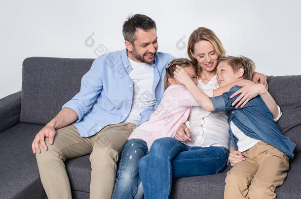 家庭和两个孩子们一次同时向沙发和热烈地拥抱