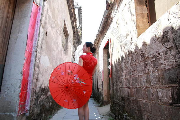 幸福的中国人女人采用红色的旗袍走采用指已提到的人胡同