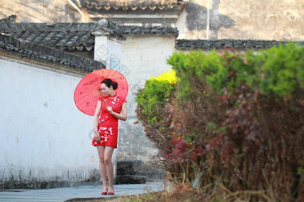幸福的中国人女人采用红色的旗袍旅行在古代的城镇