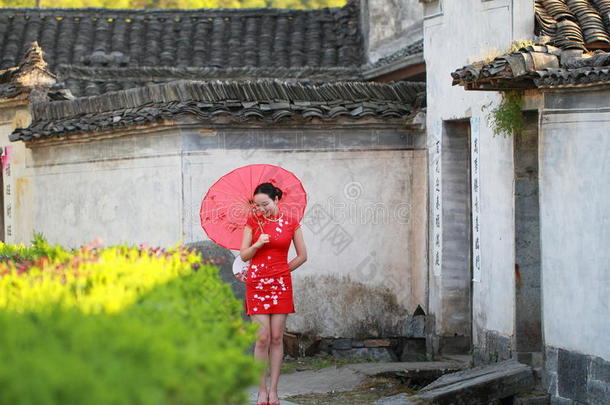 幸福的中国人女人采用红色的旗袍旅行在古代的城镇