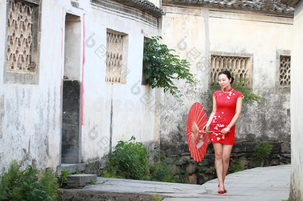 幸福的中国人女人采用红色的旗袍旅行在古代的城镇