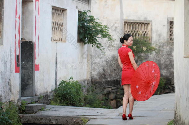 幸福的中国人女人采用红色的旗袍旅行在古代的城镇