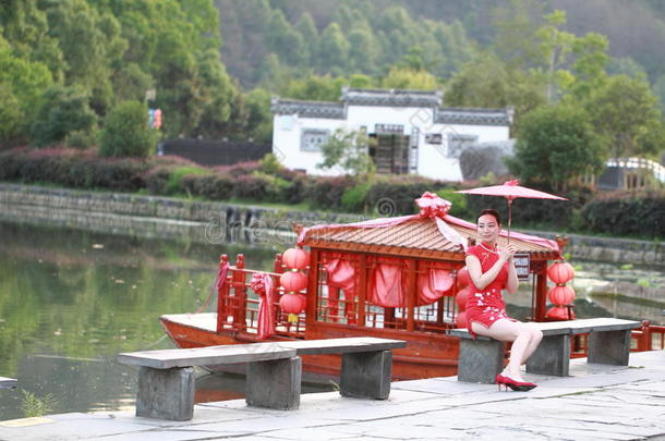 幸福的中国人女人采用红色的旗袍旅行在古代的城镇