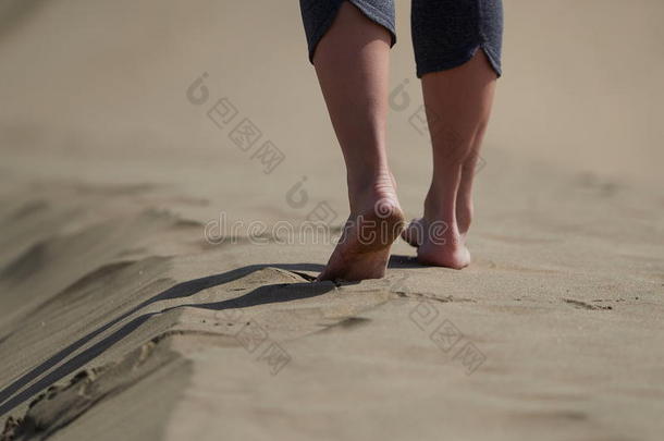 光秃秃的脚关于年幼的女人慢跑/步行向指已提到的人海滩在日出