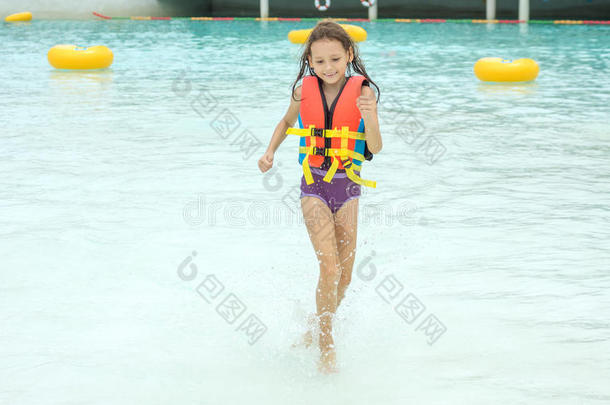 微笑的小的女孩采用生活马甲跑向水采用水公园