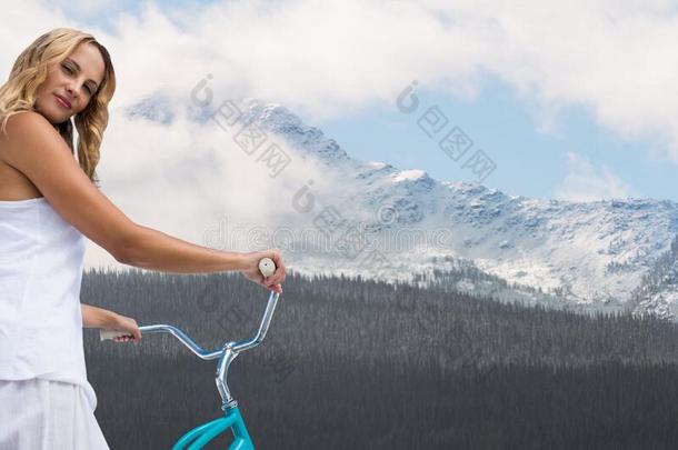 女人有样子的越过肩膀向自行车反对下雪的山winter冬天