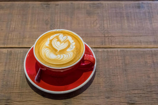 红色的咖啡豆杯子和心形状拿铁咖啡艺术向木材表
