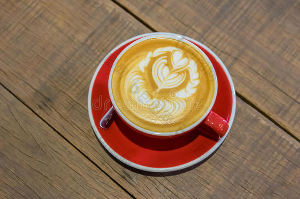 红色的咖啡豆杯子和心形状拿铁咖啡艺术向木材