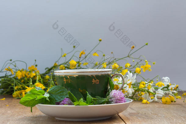 杯子和茶杯托和新鲜的薄荷树叶和三叶草花.黄色的
